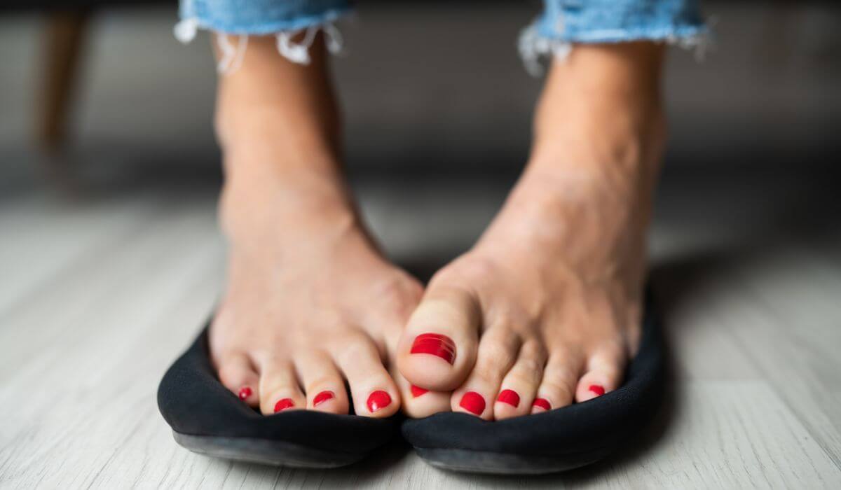 bare feet over top of flat shoes showing wider toe area.