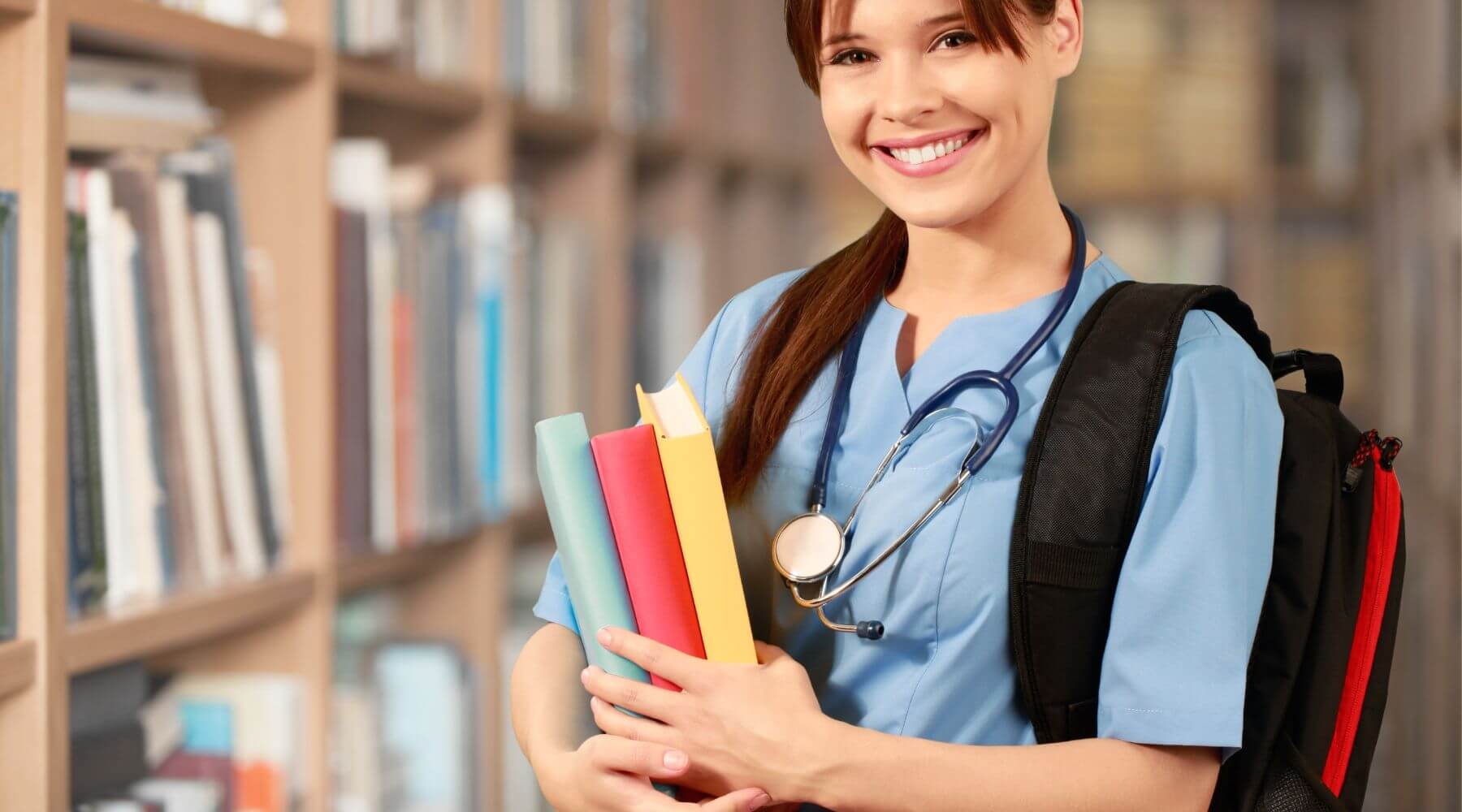 Nurse smiling with backpack and books.