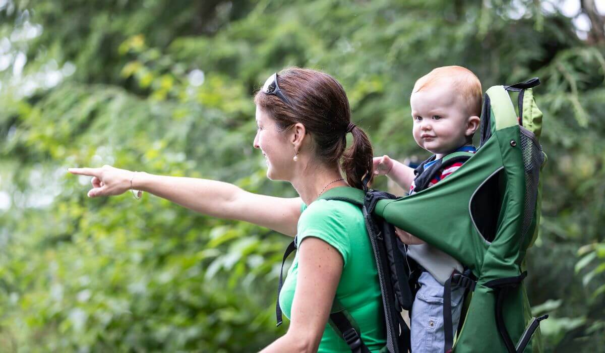 Woman with baby in baby carrier backpack on a hike.