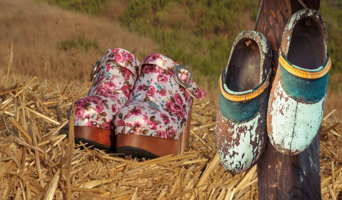 Clogs old hanging from a wood pole to newer floral version on bale of hay